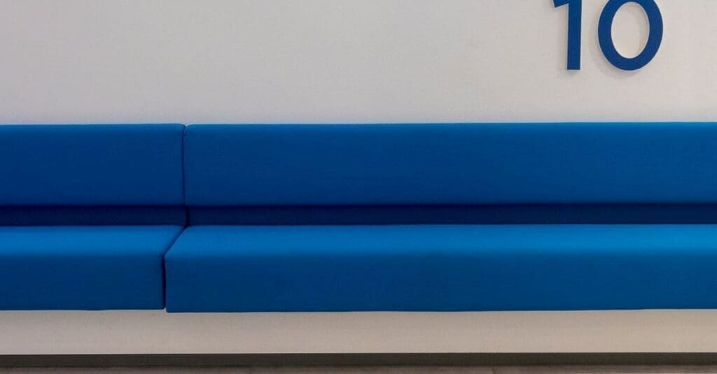 downloaded-image Blue cushioned bench seating along a white wall with the number 10 visible on the wall.